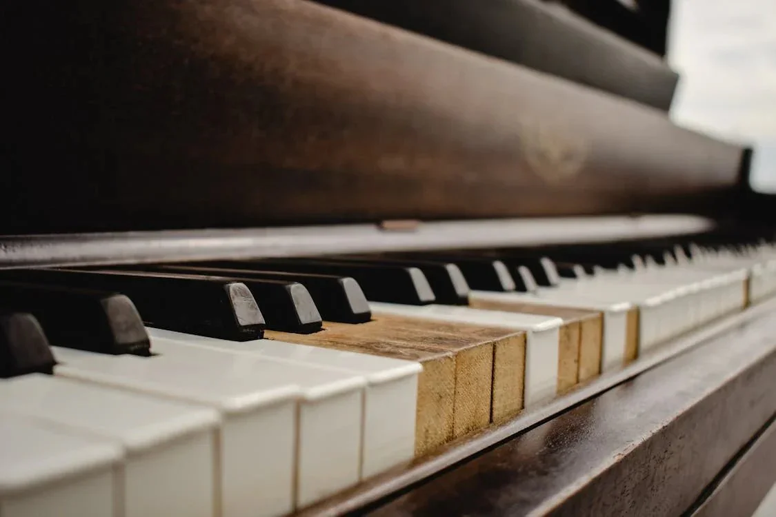 Close-up of an old piano keyboard with two key tops missing, showing the bare wood underneath